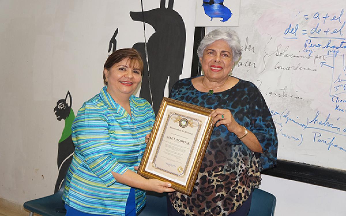 Mgter. Anays Cano de Herrera hace entrega de un pergamino a la profesora Cohen. 